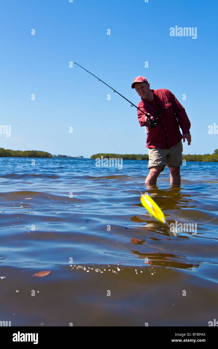 Fisherman in the water, casting his lure toward the camera. Stock Photo