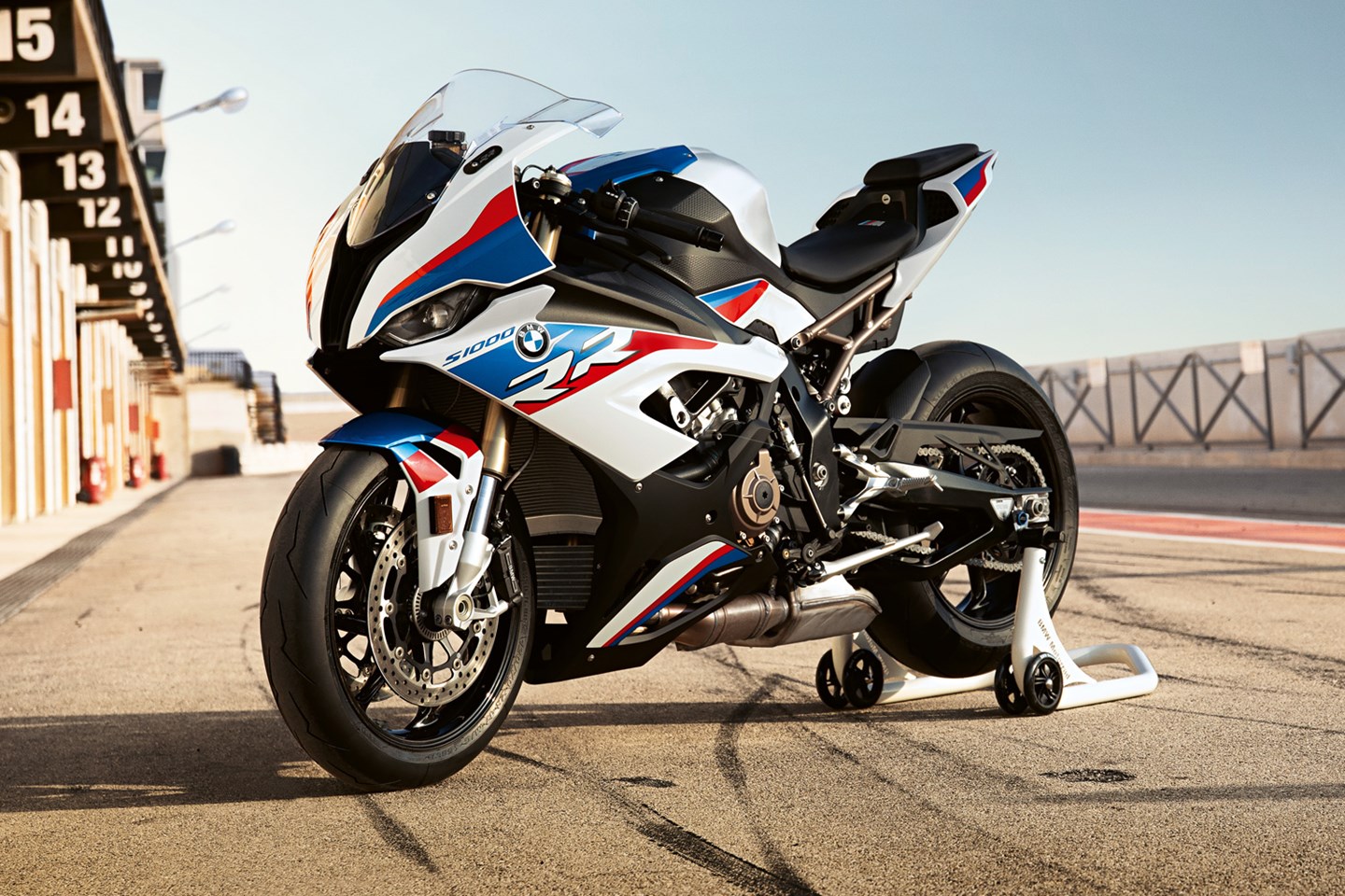 A BMW S1000RR motorcycle in the pits at a racetrack at dusk